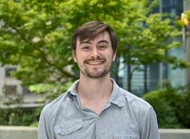 Young man with brown hair parted to the side and a mustache and beard