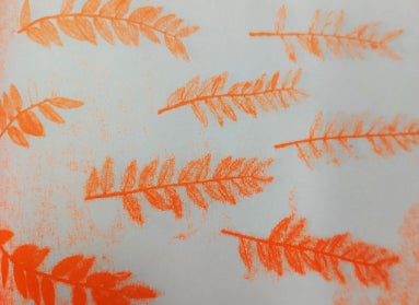 A sheet of white paper print with fern fronds in orange. 