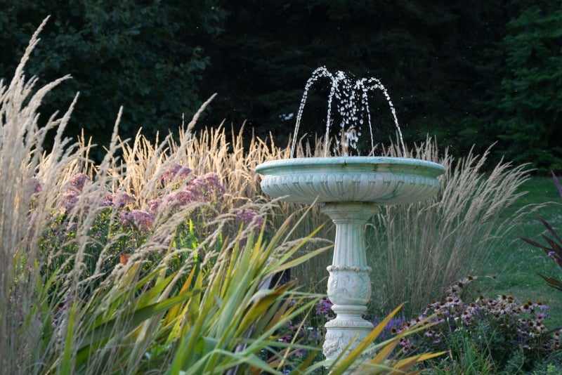 A marble fountain surrounded by pink and tan foliage. 