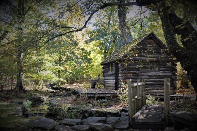 A log cabin with a wooden bridge leading up to it. 