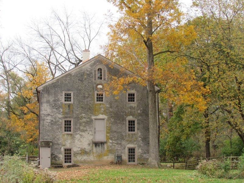 A historic mill surrounded by trees with yellow foliage. 