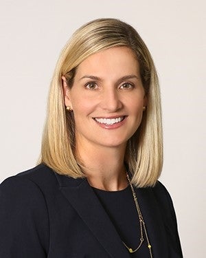 A white woman with blond hair smiles at the camera.