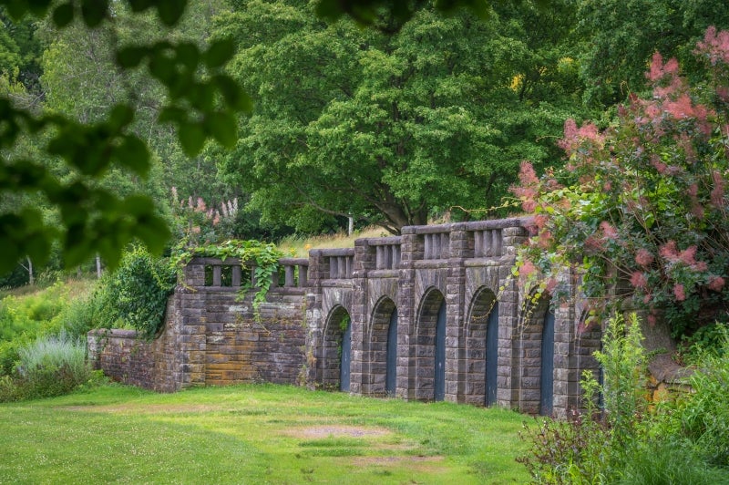 A historic stone structure with seven arches built into a green hillside
