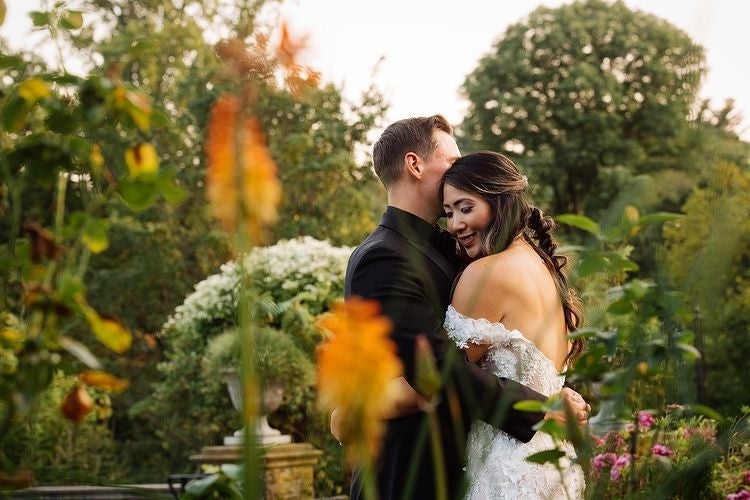 A bride and groom hug in a blooming garden. 