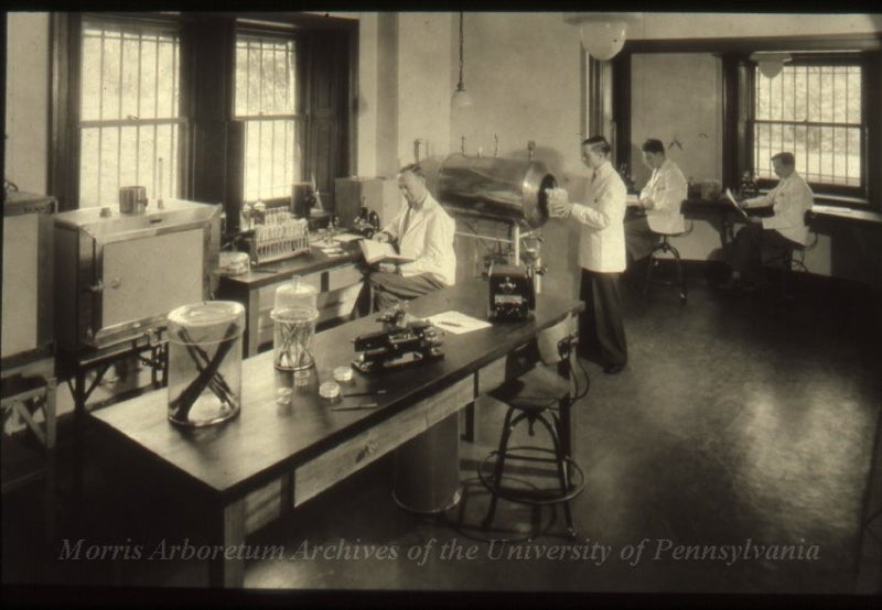 A black and white photo of scientists working in a lab.