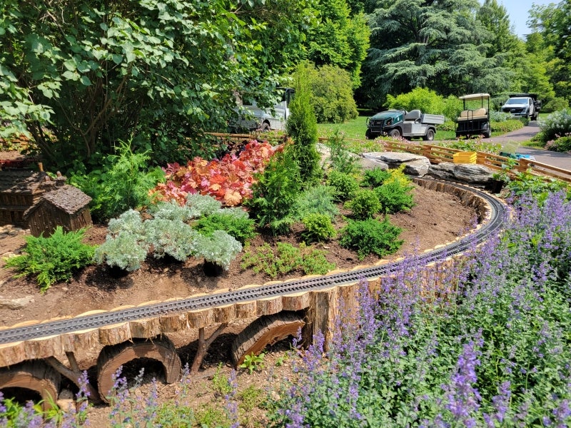A miniature railroad track set in a public garden. 
