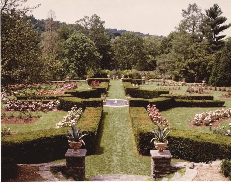 A rose garden with manicured hedges and grass paths.