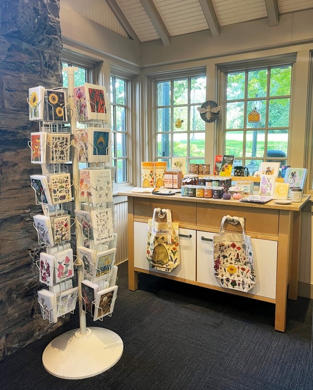 An arboretum gift shop, with a display of postcards, tote bags, and jars of honey. 