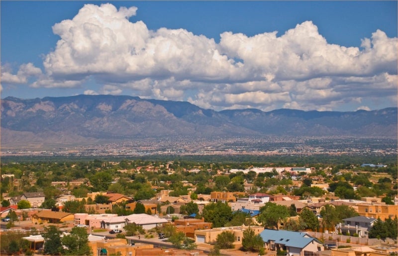 An aerial shot of Albuquerque, NM on a bright sunny day with fluffy white clouds in the blue sky. 