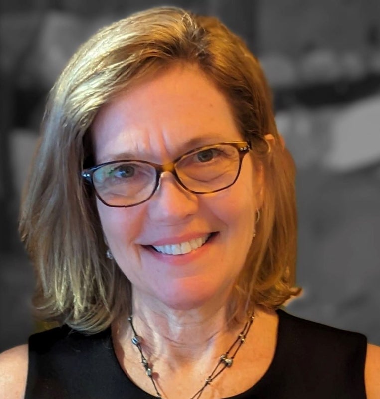 A headshot of a woman with shoulder-length blonde hair and glasses.