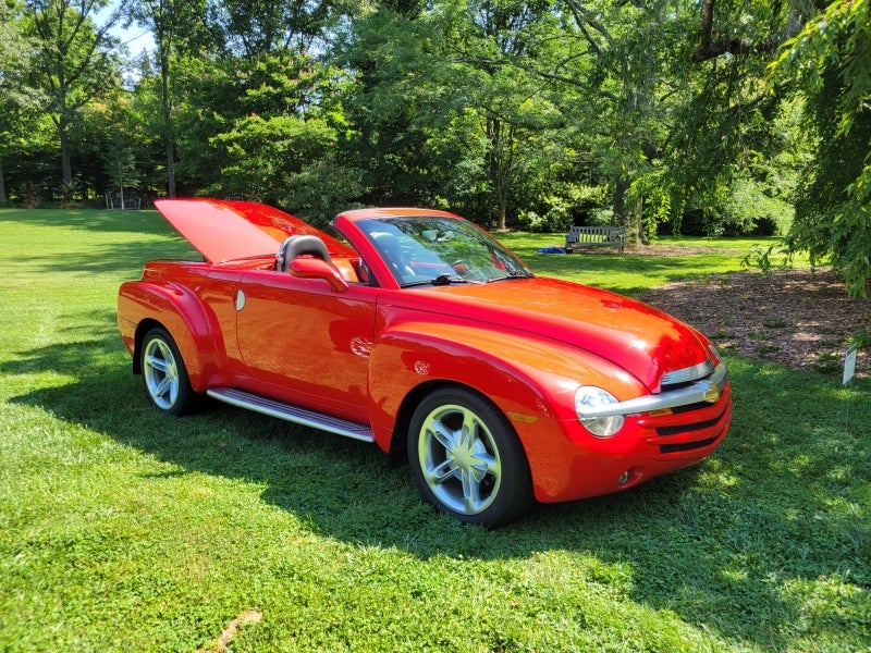 A bright red 2002 Chevrolet SSR Convertible Pickup parked on grass